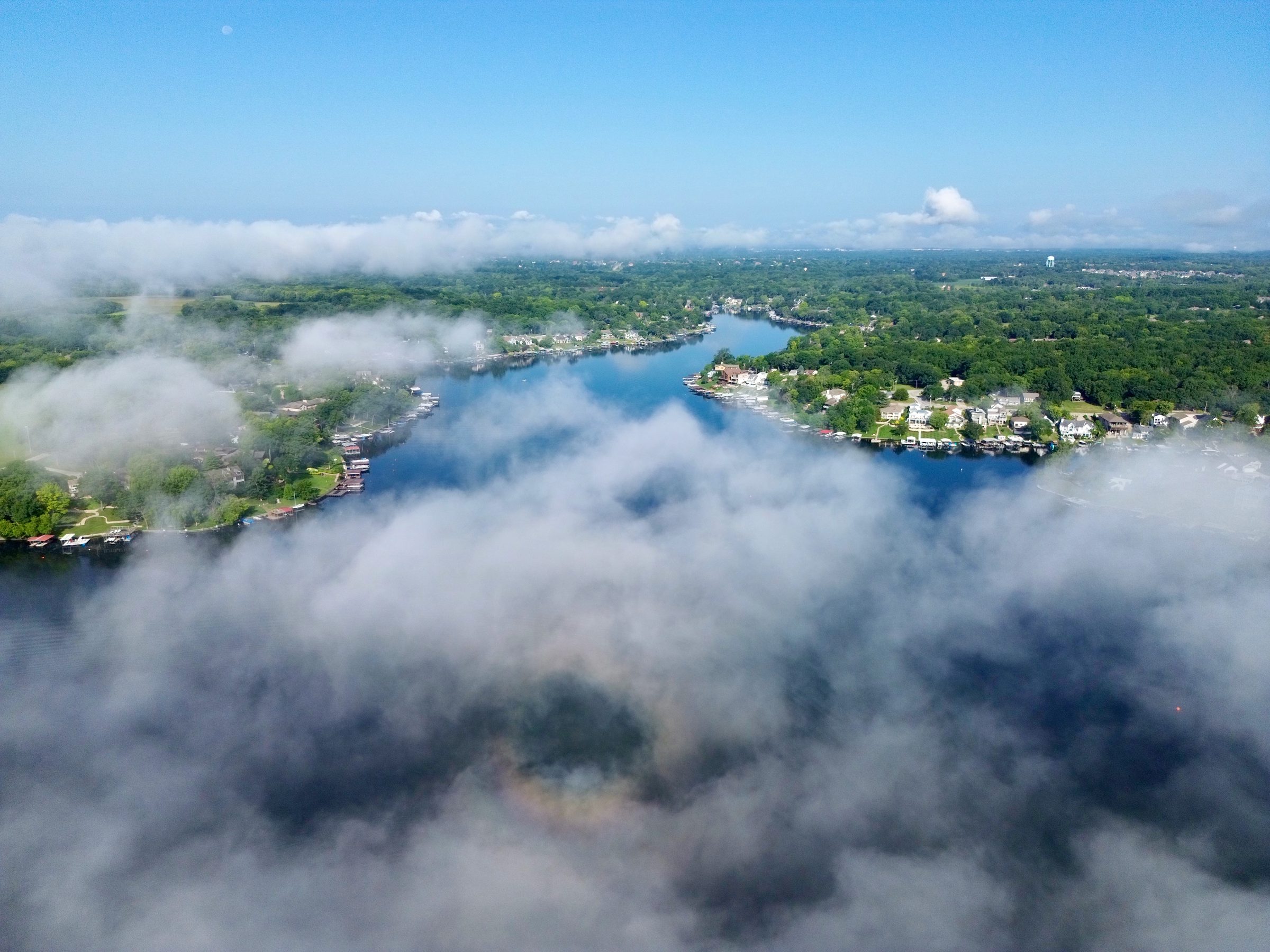 Aerial view of Lake Lotawana with morning fog drifting over the water and shoreline homes in the distance