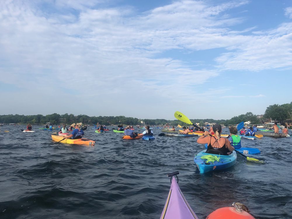 A large group of neighbors kayaking and paddleboarding together on Lake Lotawana