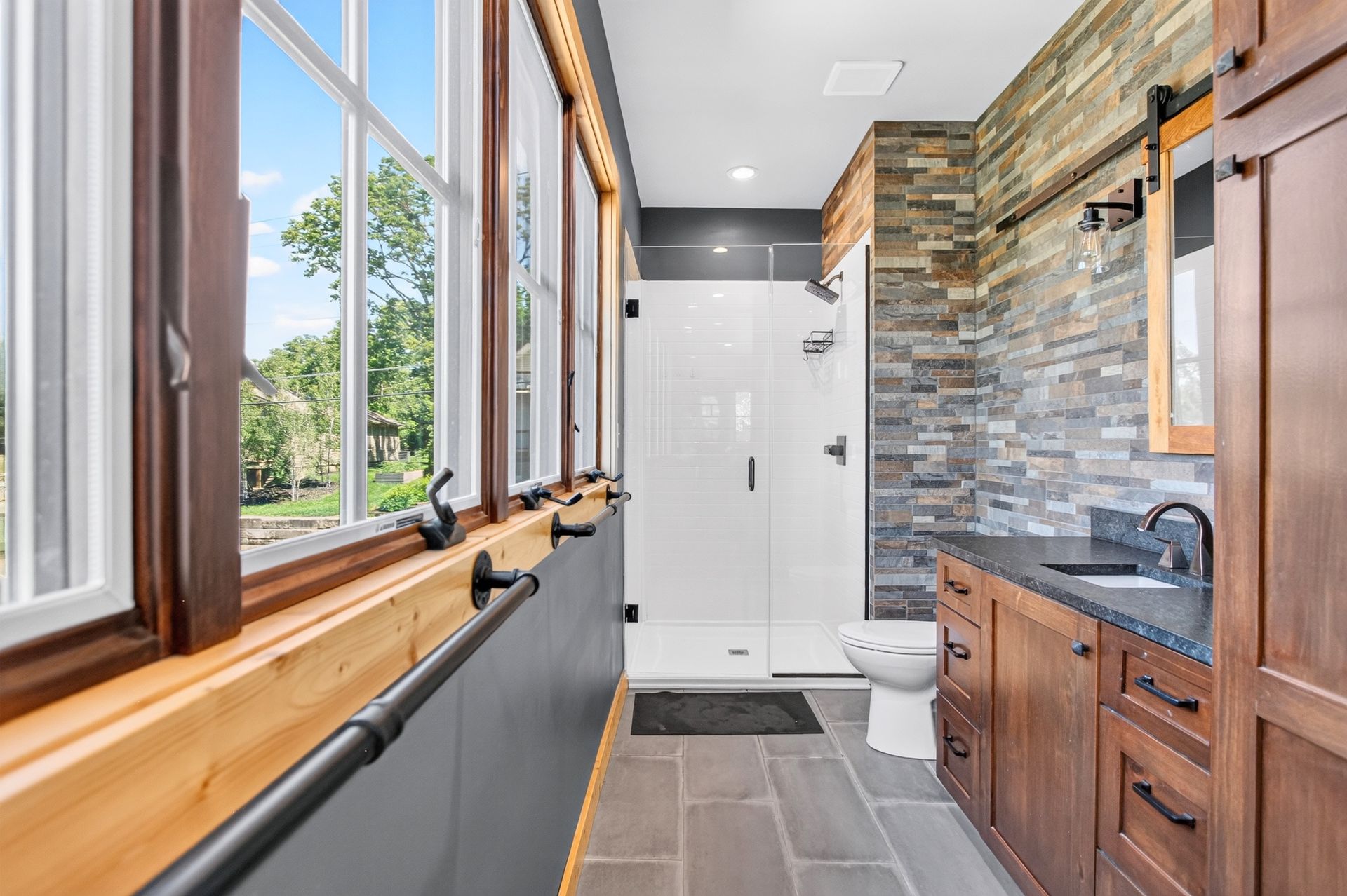 Bathroom with stacked stone accent wall and glass shower at 31 H Street, Lake Lotawana