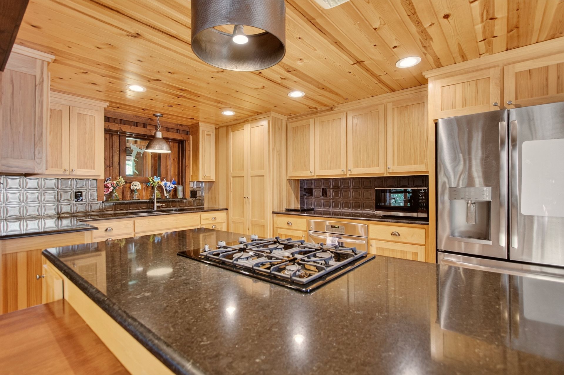 Kitchen island with gas cooktop and stainless refrigerator at 31 H Street, Lake Lotawana