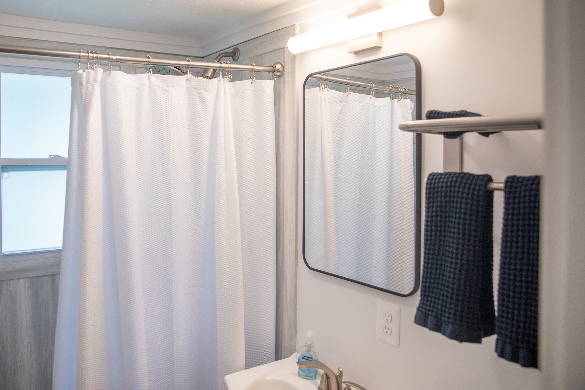 Bathroom with shower curtain and navy towels at 61 H Street, Lake Lotawana